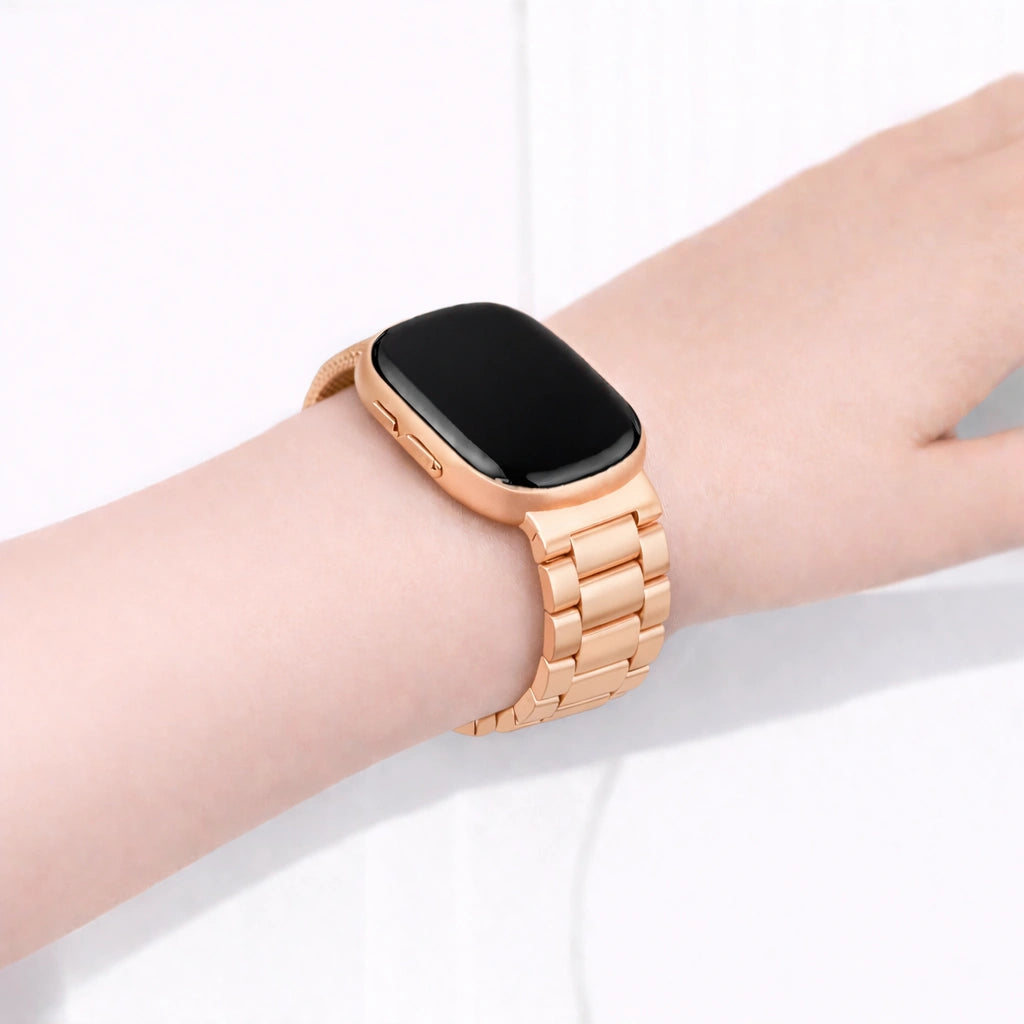 Rose gold stainless steel link watch band fitted to a Fitbit Sense 2 on the wrist, showing a secure, premium metal watch strap design