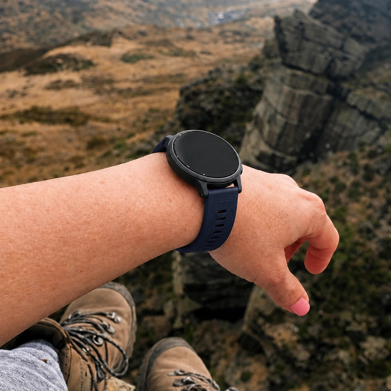 Navy blue Garmin Forerunner 165 watch band worn during a hiking adventure with scenic mountain views.