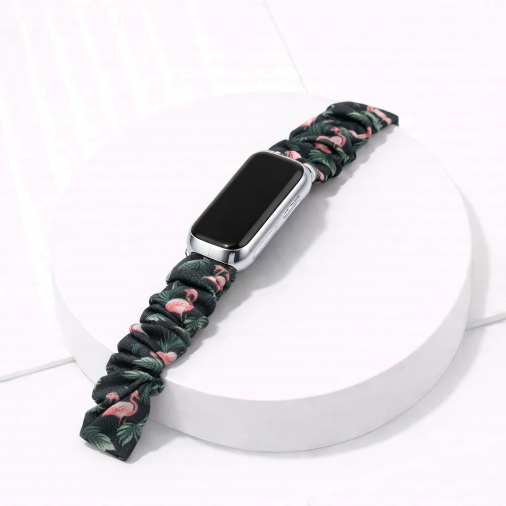Flamingo print scrunchie band for Fitbit Luxe, attached to device on a white display stand.