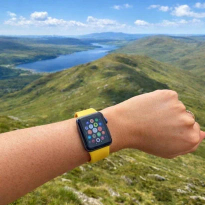 Apple Watch worn with a bright strap during a hike overlooking rolling hills and a lake