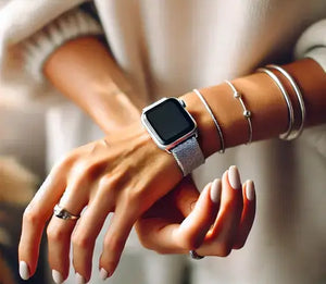 Close-up of a stylish woman’s hands wearing a silver Apple Watch strap and delicate silver bracelets, highlighting the sleek, modern aesthetic and matching neutral-toned nails.