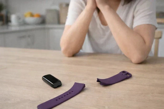 Broken Fitbit Charge 6 strap and tracker placed on a kitchen table as a woman considers whether to repair it.
