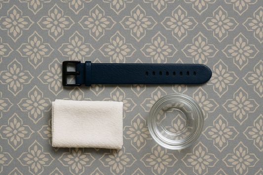 Items used to clean a leather Fitbit band, including a cloth and water.