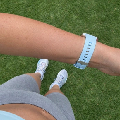 Light blue Fitbit Versa strap worn on the wrist outdoors, showing how the strap fits during everyday use