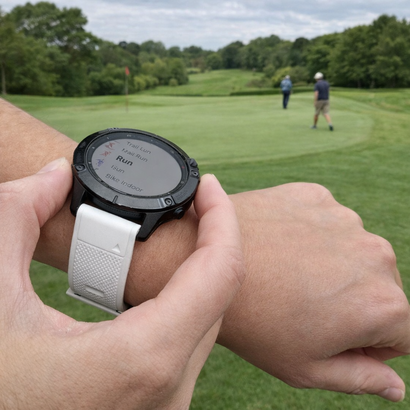 Garmin sports watch with white strap being used on a UK golf course, with golfers in the background