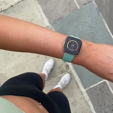 Close-up of a Fitbit Versa 2 with a green replacement strap being worn during a workout, ideal for guides on how to change the strap on Fitbit Versa 2.