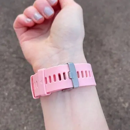 Close-up of a pink Garmin watch band with a nickel-free buckle on a wrist.