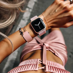 A fashionable woman wearing a pink Apple Watch band paired with delicate jewellery, styled for a chic and elegant casual look.