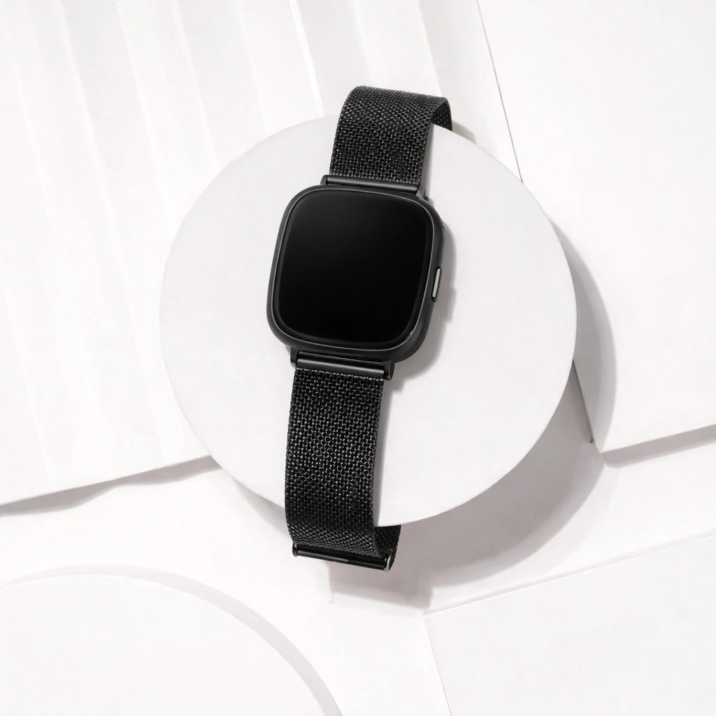 Black mesh Fitbit Versa 4 strap displayed in a clean studio setting