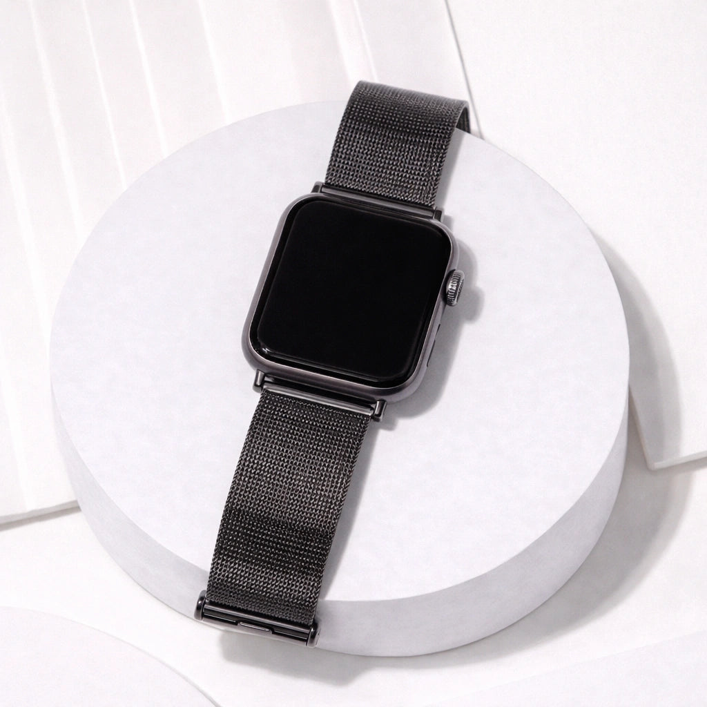 Black metal Apple Watch band displayed on a stand with a breathable mesh design