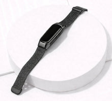 Black Milanese strap for Fitbit Inspire 3 displayed on a stand