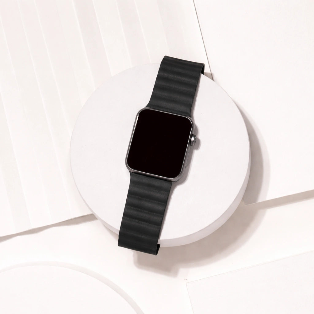 Black two-part leather Apple Watch strap displayed on a white platform.