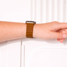 Brown leather Apple Watch wristband worn on the wrist.