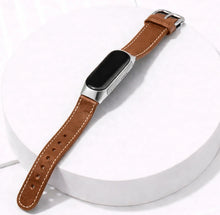 Brown leather strap for Fitbit Inspire 3 shown on a display stand