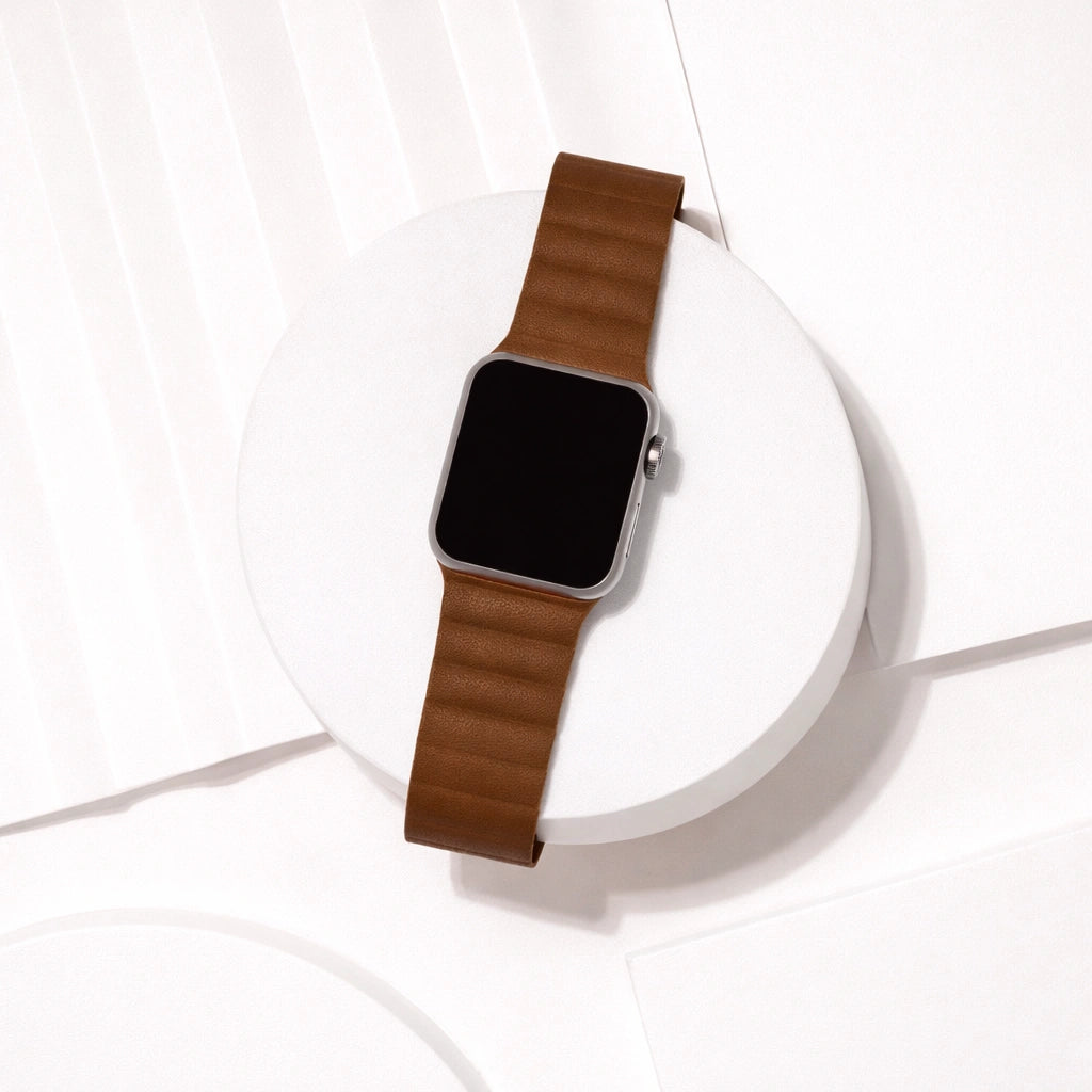 Brown two-part leather Apple Watch strap displayed on a white platform.