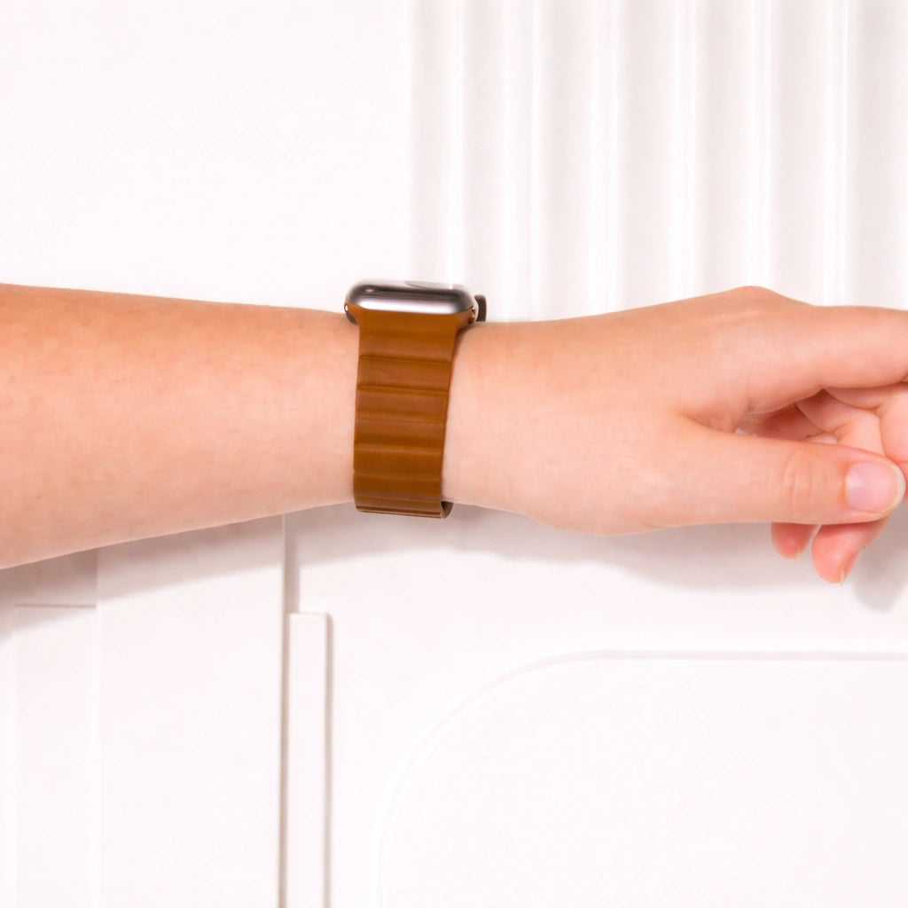 Brown two-part leather Apple Watch wristband worn on the wrist.