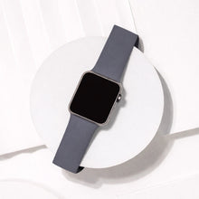 Dark grey silicone Apple Watch strap flat lay on white stand showing smooth flexible band design.