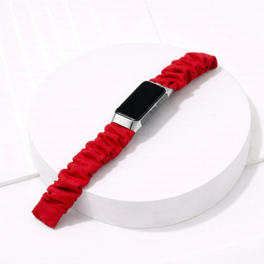 Red scrunchie strap for Fitbit Charge 5 displayed on a white pedestal flatlay at an angled position