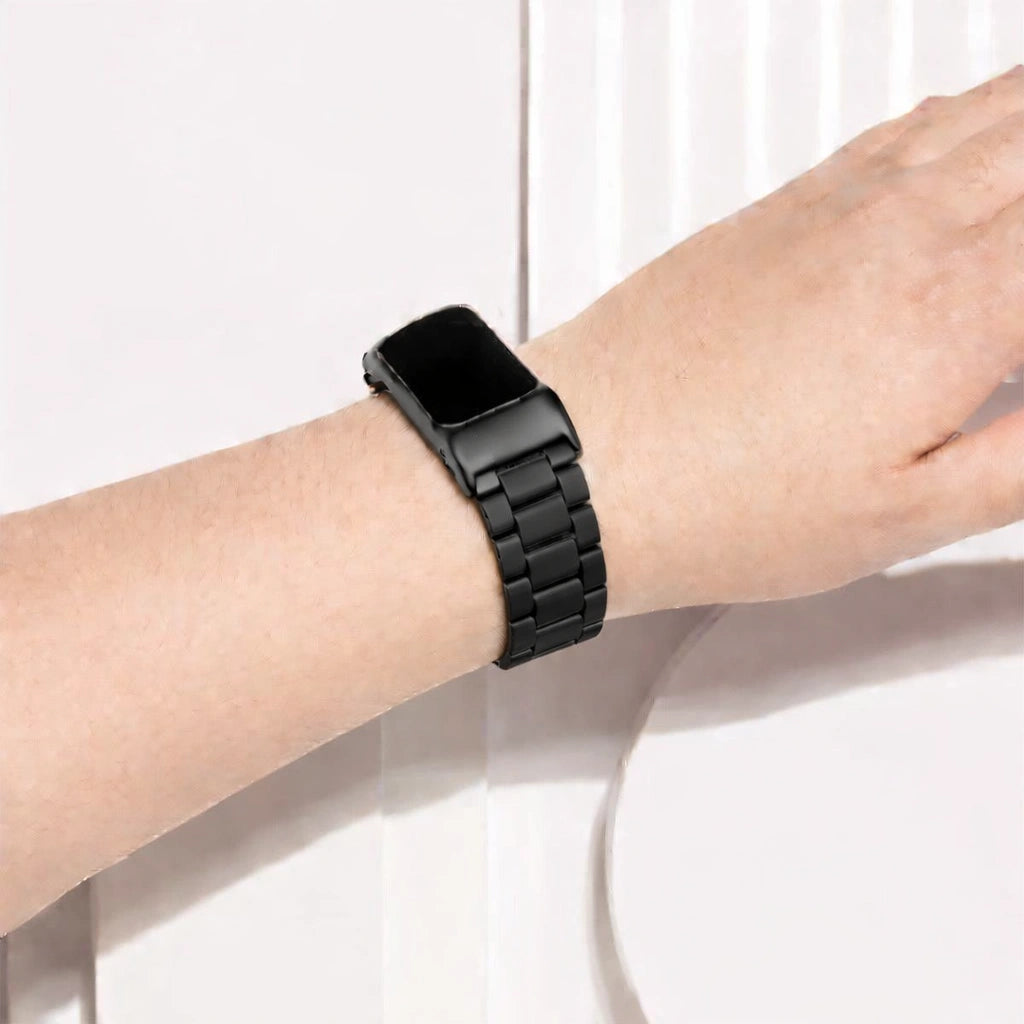 Metallic black stainless steel link strap worn on the wrist with Fitbit Charge 6