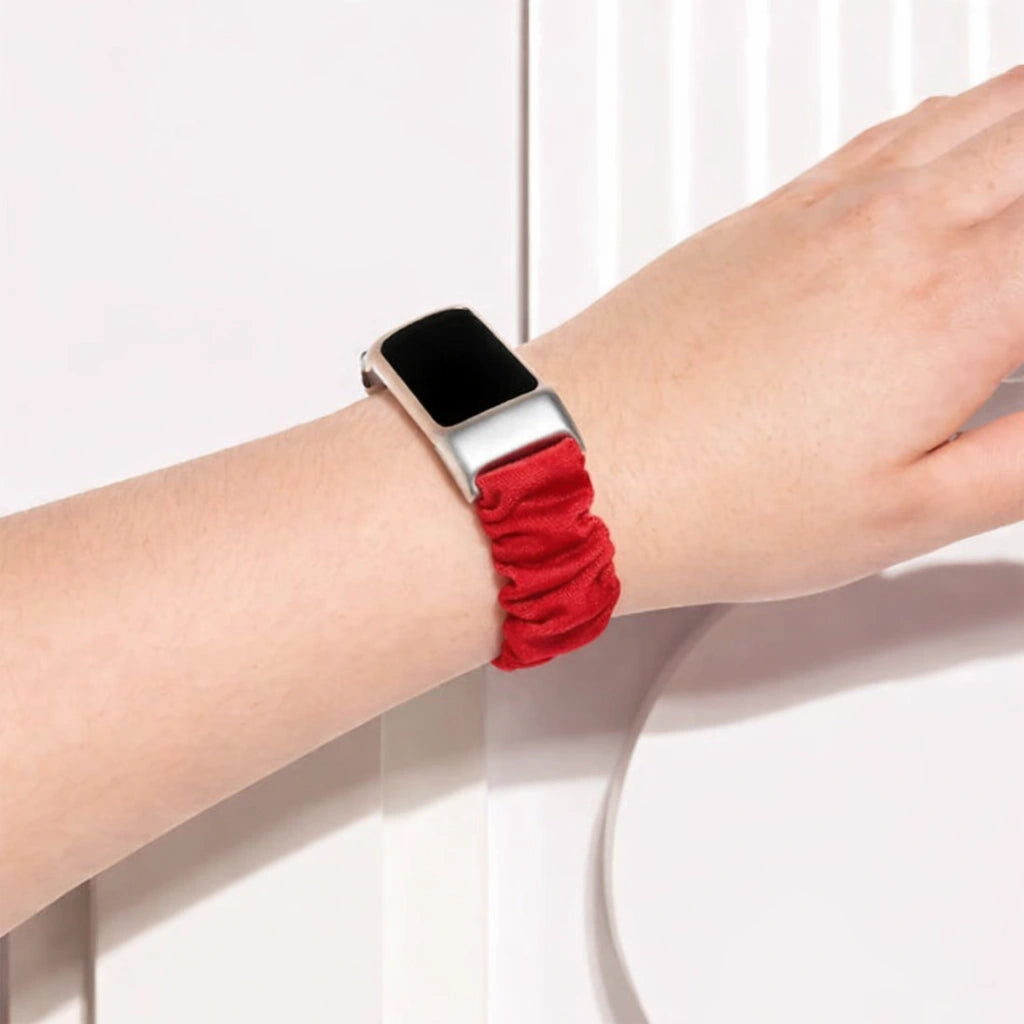 Fitbit Charge 6 worn with a red fabric scrunchie strap on the wrist