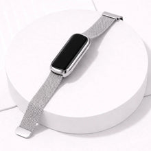 Silver mesh Fitbit Luxe straps attached to rounded Luxe tracker displayed on white stand