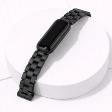 Fitbit Luxe black metal bracelet watch strap attached to tracker on white display stand