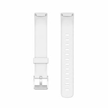 White silicone Fitbit Luxe straps shown in flat lay with silver buckle and adjustable strap holes