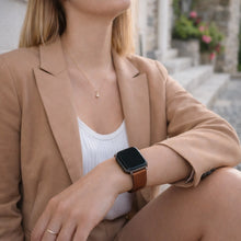 Brown leather strap for Fitbit Versa 2 worn with a smart outfit outdoors, showing a classic everyday look.