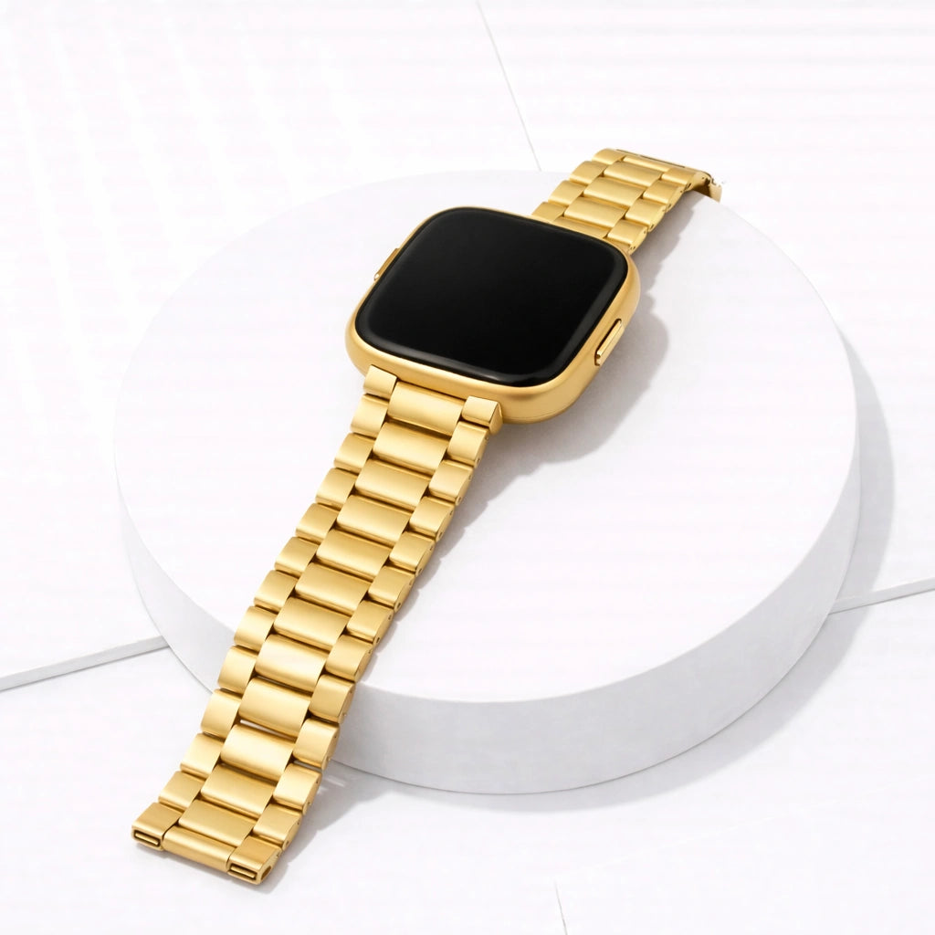 Gold stainless steel watch strap for Fitbit Versa 2 displayed on a stand