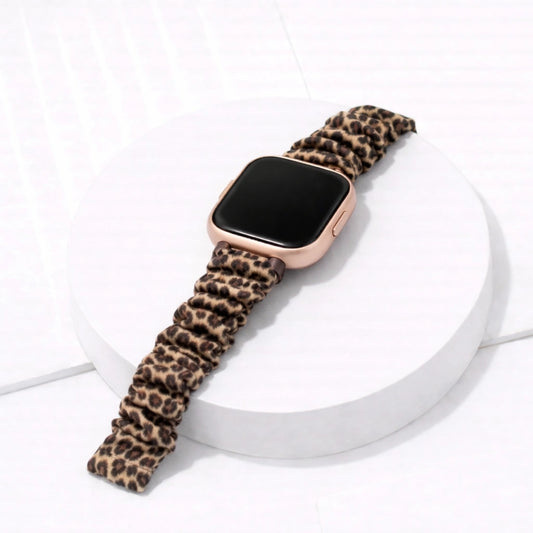 Leopard print scrunchie watch strap attached to a Fitbit Versa 2 on a display stand
