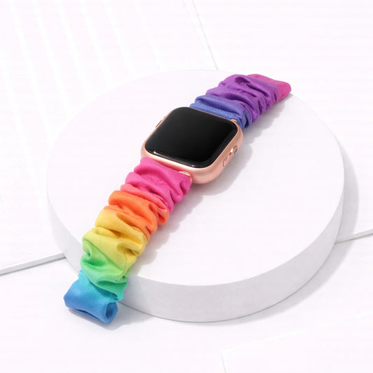 Rainbow colour scrunchie strap fitted to a Fitbit Versa 2 in a flat lay style