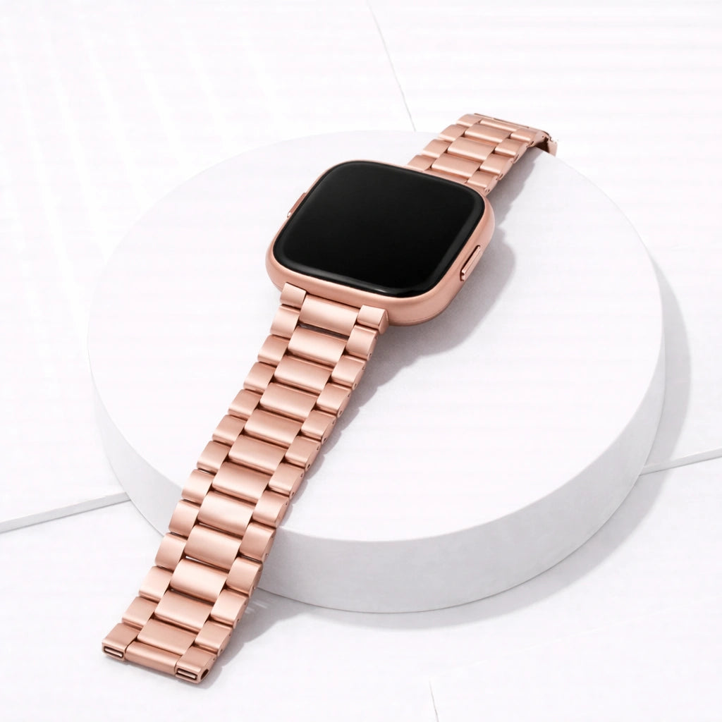Rose gold stainless steel watch band for Fitbit Versa 2 displayed on a stand