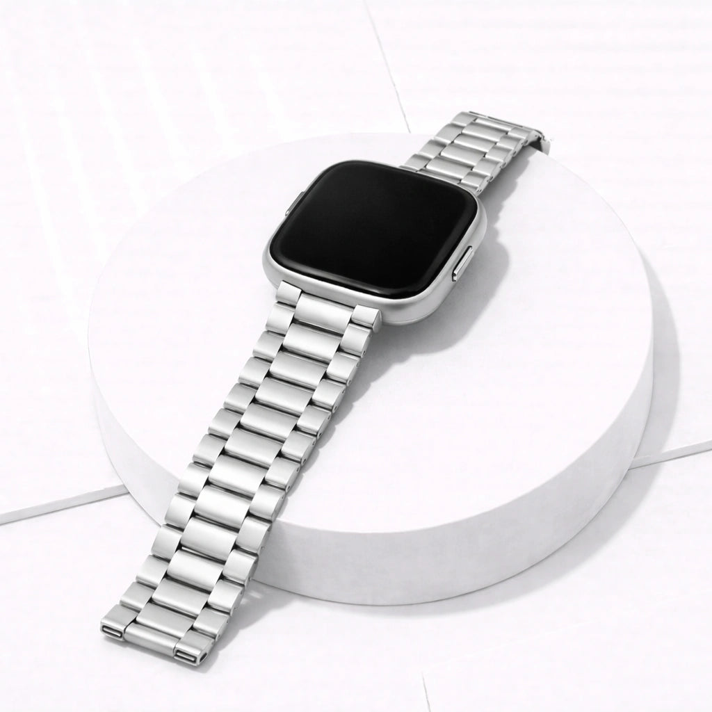 Silver stainless steel strap for Fitbit Versa 2 displayed on stand