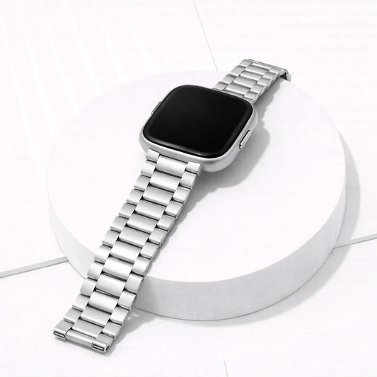 Silver stainless steel strap for Fitbit Versa 2 displayed on stand