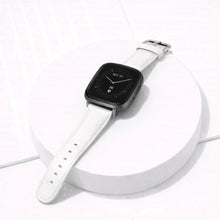 White leather band for Fitbit Versa 3 displayed on a stand, featuring a soft leather finish and adjustable buckle.