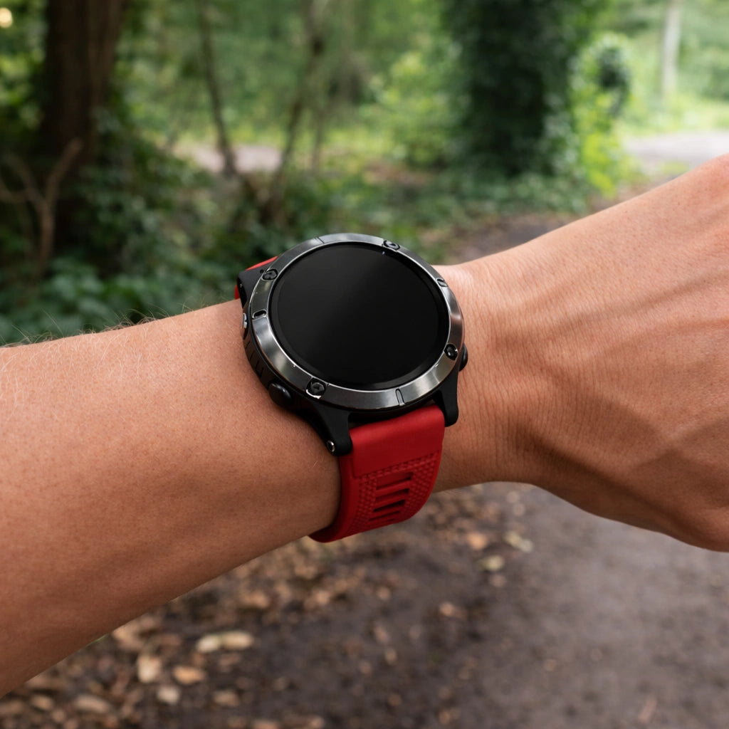 Red band for Garmin Forerunner 965 worn outdoors during running on a forest path