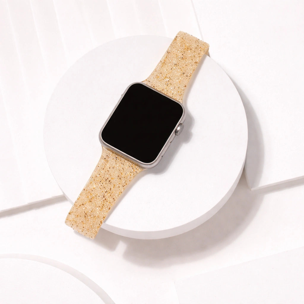 Gold glitter Apple Watch band displayed on a white circular platform with shimmering textured finish