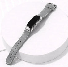 Grey leather strap for Fitbit Inspire 3 shown on a display stand