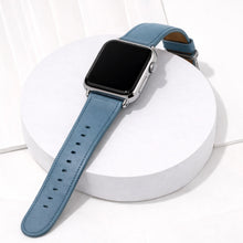 Light blue leather Apple Watch wristband displayed on a white stand.