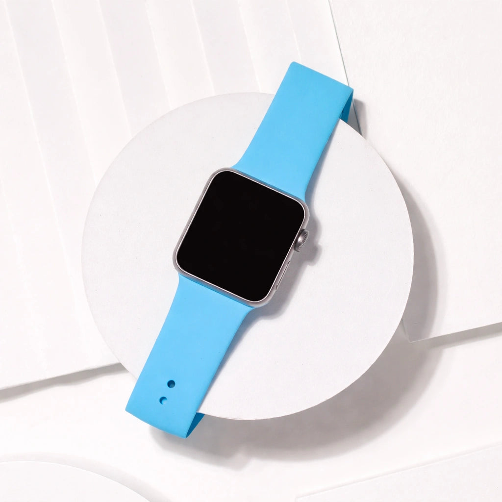 Light blue silicone Apple Watch strap flat lay on white stand showing smooth flexible band design.
