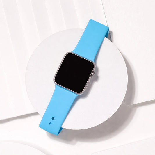 Light blue silicone Apple Watch strap flat lay on white stand showing smooth flexible band design.