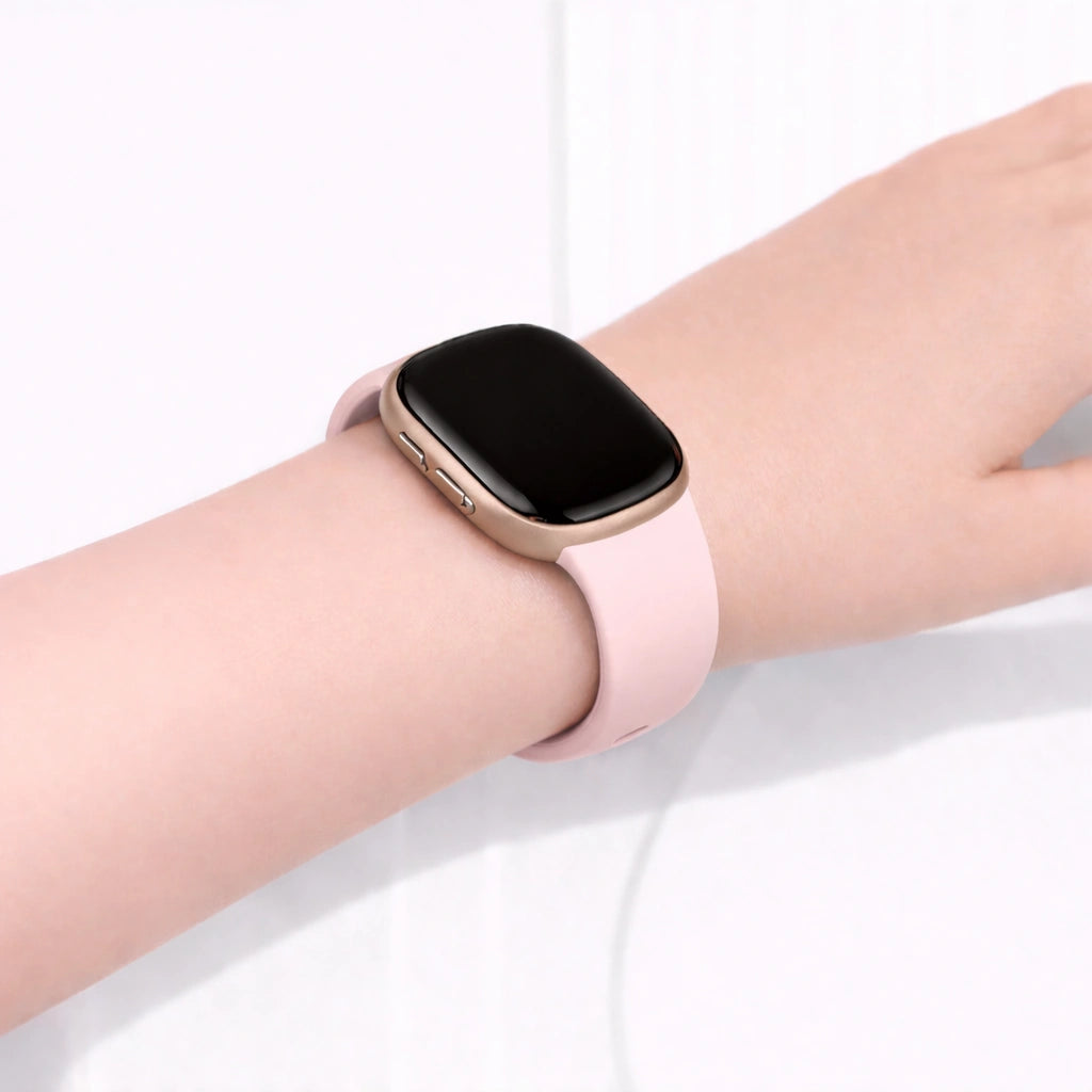 Silicone wristband for Fitbit Versa 3 in light pink worn on the wrist.