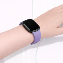 Light purple watch strap worn on wrist, designed as a comfortable replacement strap for Fitbit Versa 3