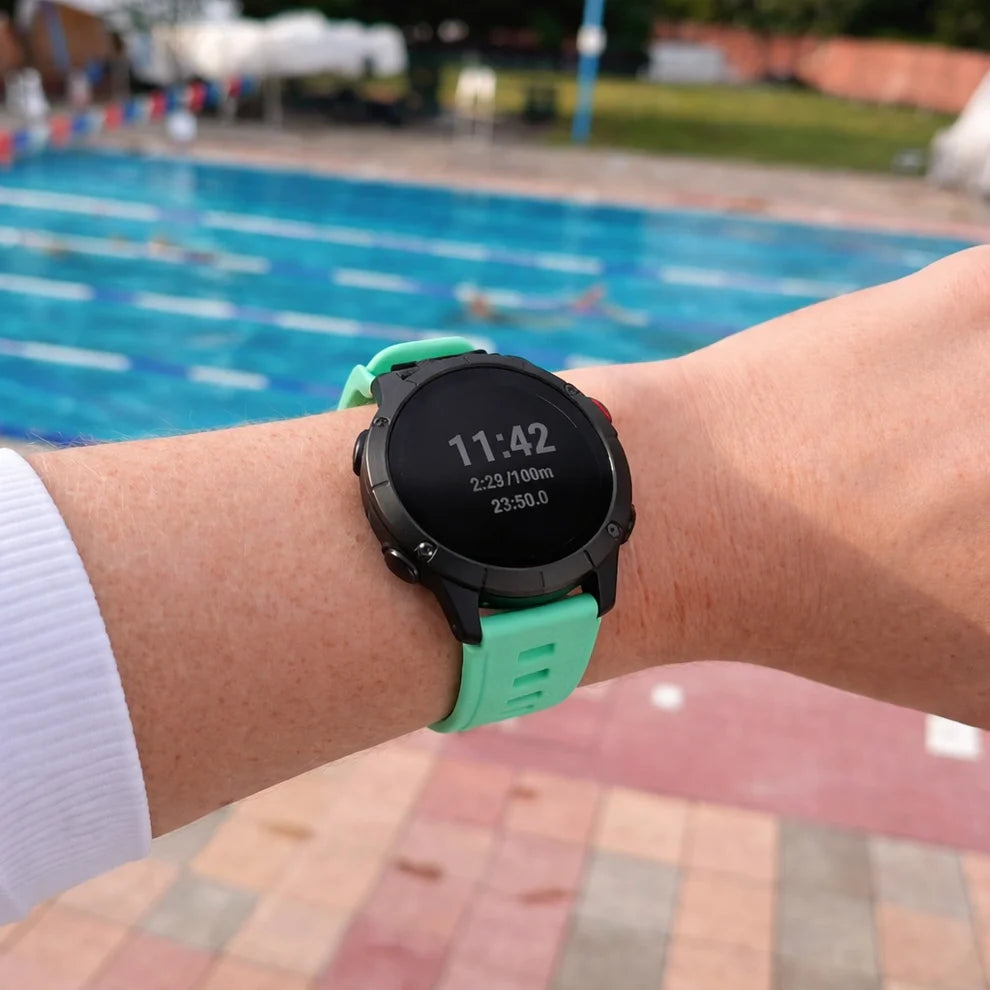 Mint Garmin Instinct 3 watch strap worn beside an outdoor swimming pool