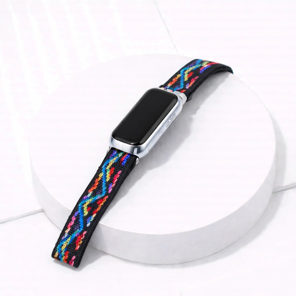 Multi colour zigzag Fitbit luxe band attached to tracker on a white display stand
