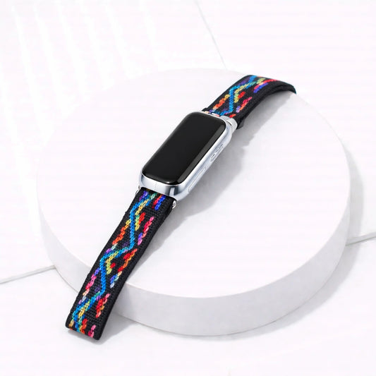 Multi colour zigzag Fitbit luxe band attached to tracker on a white display stand