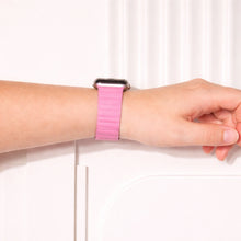 Pink leather Apple Watch band worn on the wrist.