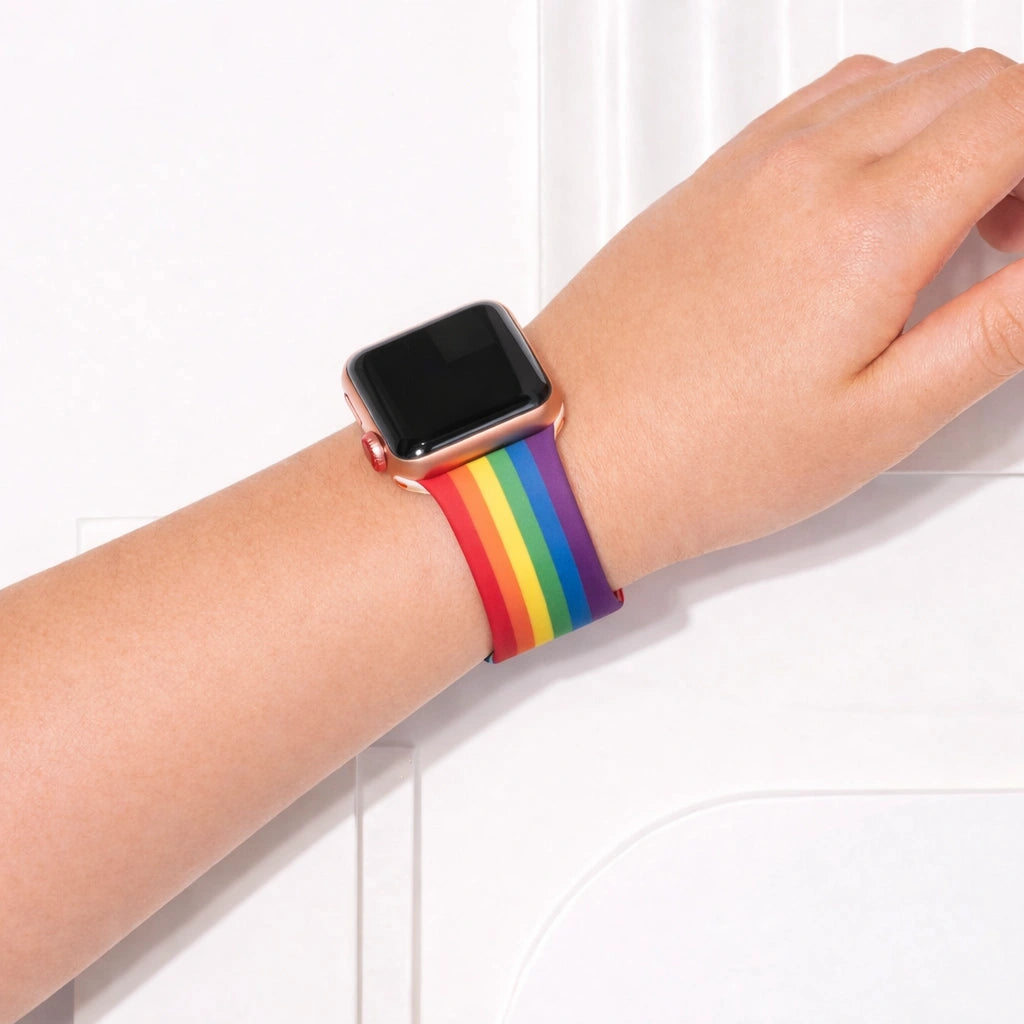 Apple Watch worn on wrist with colourful rainbow pattern silicone band.