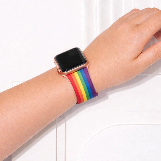 Apple Watch worn on wrist with colourful rainbow pattern silicone band.