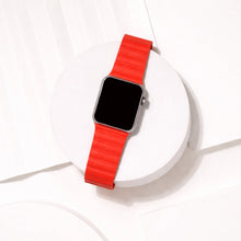 Red two-part leather strap for Apple Watch displayed on a white platform.